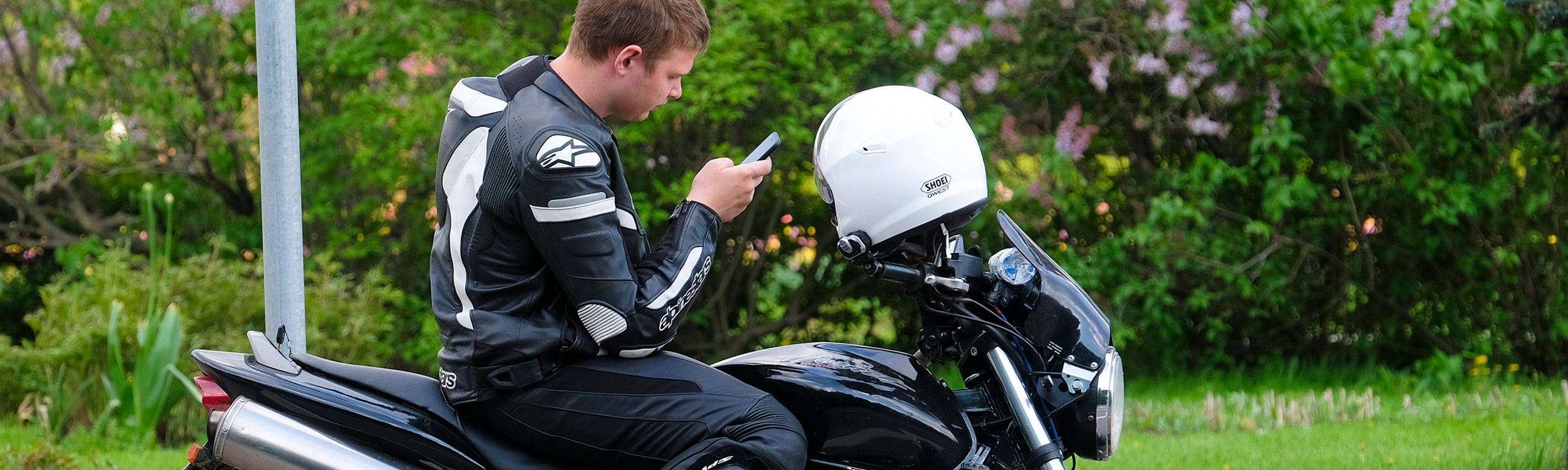Motorcycle rider parked while checking mobile phone.